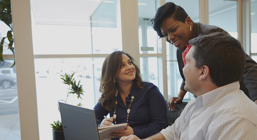 Multi-ethnic team of smiling professionals around computer